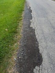 Road with a crack in it and grass growing on the side