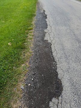 Road with a crack in it and grass growing on the side