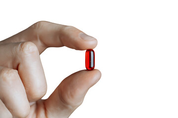 Close up of a hand holding a single red capsule.