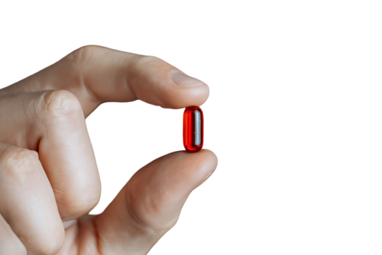Close up of a hand holding a single red capsule.