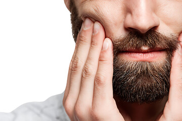 Fototapeta premium Close up of a man with a beard holding his jaw in pain.