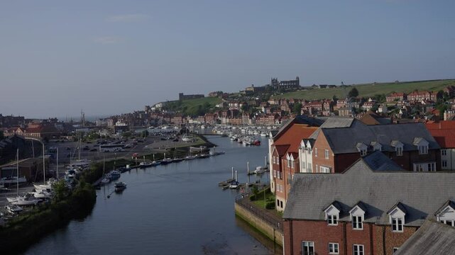 River Esk flowing through Whitby harbor connecting to North Sea with Whitby Abbey on the East Cliff in North York Moors National Park, England, United Kingdom