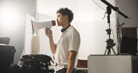 Man, director and megaphone for filming backstage of shooting, acting tips and schedule. Supervisor, speaker and bullhorn with cinematography plan, performance guide and crew feedback for production © Lahoud25/peopleimages.com
