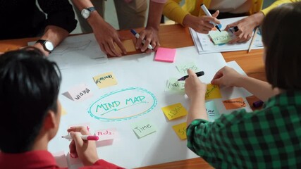 Top view of business team in casual cloth hand writing idea on sticky notes. Closeup of diverse people brainstorming marketing idea while sticking colorful sticky notes on mind mapping. Convocation.