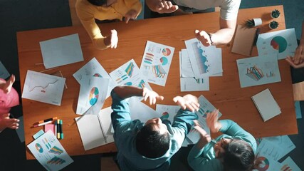 Top view of smart people throw paper and giving high five at meeting table with financial document and stock market analysis paper scattering around. Aerial view of team celebrate project. Symposium. - Powered by Adobe