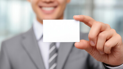 Fototapeta premium Clear white business card for copy space, holding by blurred smiling businessman in suit.