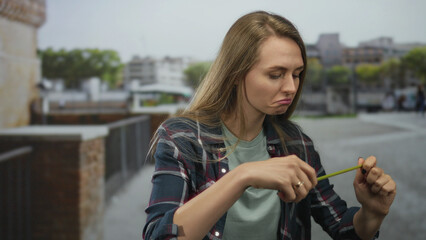 Woman on city street examining tape measure outdoors with focused expression, surrounded by urban...