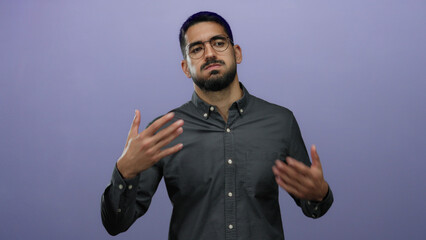 Young hispanic man with glasses posing against a purple background, wearing a dark shirt, looking expressive and thoughtful.