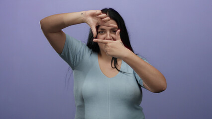 Woman making a frame gesture with hands over isolated purple background wearing light blue top,...
