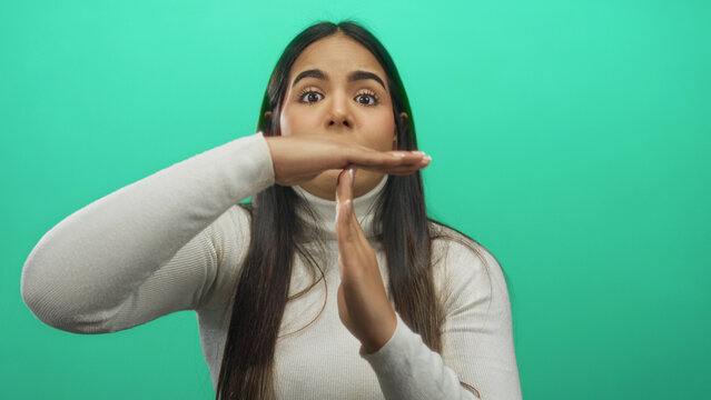 Young woman signaling timeout over isolated green background suggesting pause or break in communication or activity in a casual setting. - Powered by Adobe