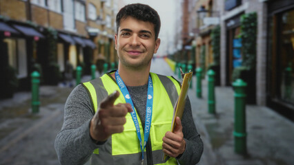 Man lifts hand while pointing at street with young hispanic volunteer holding clipboard beside guy...