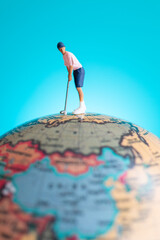 A miniature figure of a golfer playing on top of a globe