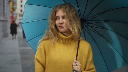Woman umbrella holding street scenes feature blonde hair over yellow sweater beneath blue canopy...