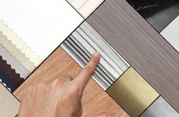 interior designer's hand choosing material palette samples featuring a diverse range of textures: elegant wood, luxurious marble, versatile tiles, stainless and soft fabrics in neutral color scheme.