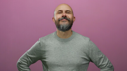 Obraz premium Bearded man with bald head stands confidently against isolated pink background conveying positive and approachable vibe