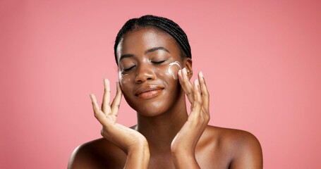 Black woman, lotion and skincare with face cream in studio for moisturizer on a pink background. Female person, model and applying cosmetics for skin protection, anti aging or sunscreen on space