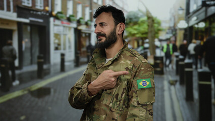 Military man with a beard in camouflage uniform points at a brazilian flag patch while standing on...