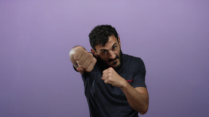 Hispanic man with beard in fighting stance against a purple background showing confidence and...