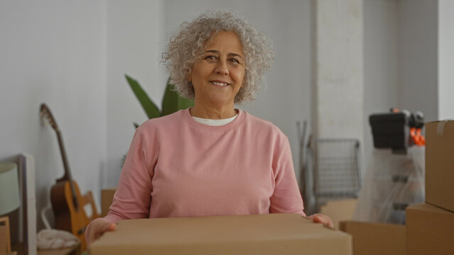 Woman packing boxes in a living room while moving into a new home, reflecting a middle-aged individual's transition to a new residential setting.