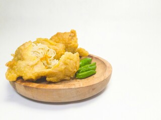 Fried tofu (filled tofu) served with green chilies on a wooden plate. This traditional snack is commonly found at street stalls throughout Indonesia.