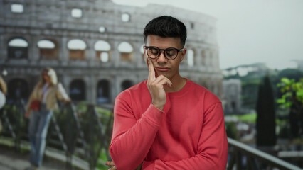 Young man contemplating in front of the historic roman coliseum, outdoors in rome