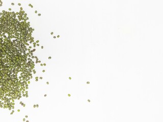 Scattered green mung beans on a clean white background. A minimal food concept showing healthy and...