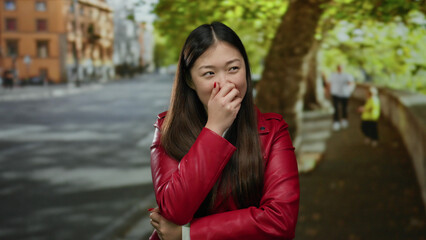 Woman in red jacket smiling on urban street with trees and buildings in the background