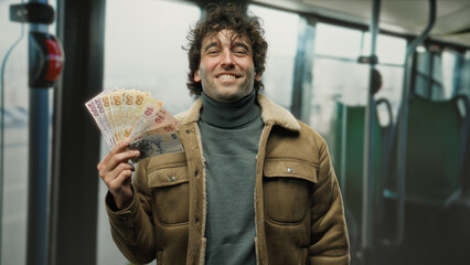 Hispanic man holding turkish lira banknotes smiles on a bus, highlighting an indoor scene of...
