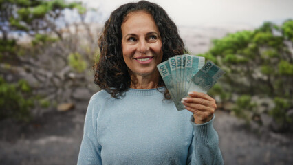 Woman holding brazilian money, smiling in a garden, representing financial success in brazil with...