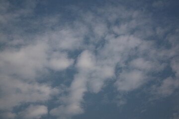 A sky is filled with irregularly shaped clouds, creating dynamic patterns against a dark, bluish-gray background. 