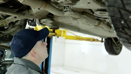 Skilled mechanic in protective gear carefully tightening chassis bolts, performing precise maintenance for vehicle reliability and operational efficiency