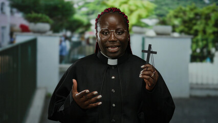 Woman preacher holding cross on city street with outdoor background and urban setting, expressing...