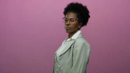 Woman standing confidently against isolated pink background wearing glasses and blazer over white...