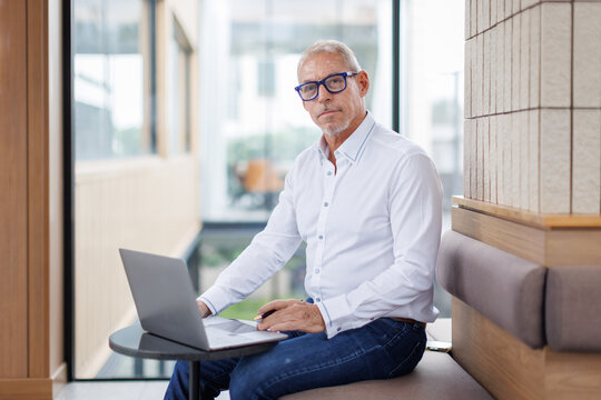 Business portrait of confident business middle aged man. Entrepreneur in white shirt, Senior adult, mature age man susing laptop on office background.

