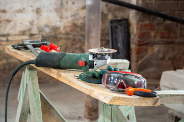 Power tools and safety equipment rest on a wooden workbench in a renovation project exposed to...