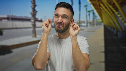 Young man outdoors in city making mock crying gesture with a playful expression against an urban...