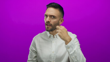 Obraz premium Hispanic man gesturing expressively against vibrant purple background while wearing a white shirt, showing dynamic communication and engaging emotive style.
