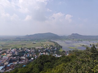 A spiritually resonant view of Thirukazhukundram, Tamil Nadu, India, capturing both the hilltop Vedagiriswarar Temple and the ancient foothill temple complex. The hill temple, dedicated to Lord Shiva,