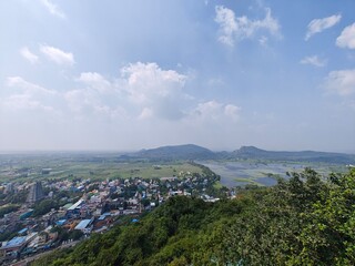 A spiritually resonant view of Thirukazhukundram, Tamil Nadu, India, capturing both the hilltop Vedagiriswarar Temple and the ancient foothill temple complex. The hill temple, dedicated to Lord Shiva,