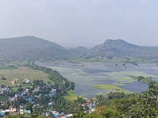 A spiritually resonant view of Thirukazhukundram, Tamil Nadu, India, capturing both the hilltop Vedagiriswarar Temple and the ancient foothill temple complex. The hill temple, dedicated to Lord Shiva,