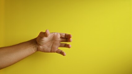 Man's hand with fingers extended against a vibrant yellow background conveying a clear gesture