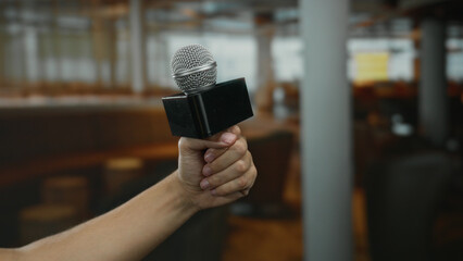Man holding microphone indoors at hotel setting, capturing the essence of a caucasian male presence...
