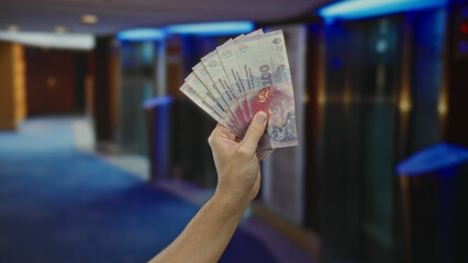 Male hand holds argentine pesos inside a luxurious hotel setting, highlighting finance, travel, and...