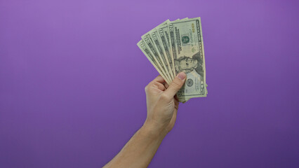 Caucasian man holding united states dollars with a purple background, showcasing american banknotes...