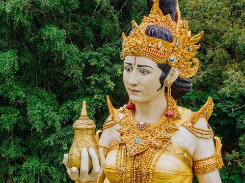 Statue of a deity in Danau Batur. The statue is adorned with gold jewelry and a crown, and is holding a golden vessel. Dewi Danu, Bali, Indonesia