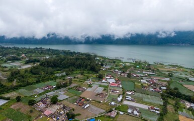Aerial view of Lake Batur, Bali, Indonesia, showing the local village and farmland. The community...