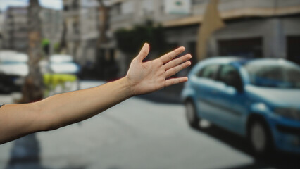 Man extending hand on busy city street signals gesture with cars in background illustrating urban...