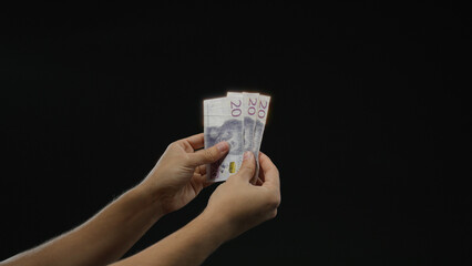 Man holding swedish krona banknotes over isolated black background, highlighting financial concepts...