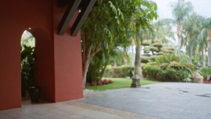 Blurred view of a luxury tropical resort's lush outdoor area with palm trees and elegant architecture creates a serene and inviting atmosphere perfect for relaxation.