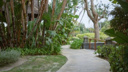 Blurred tropical resort pathway with lush greenery and exotic plants creates a serene outdoor luxury escape, offering a peaceful and inviting ambiance for relaxation.